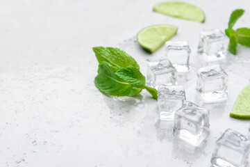 Ice cubes, mint and lime on light background
