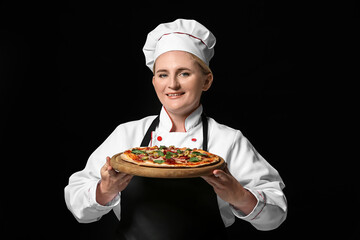 Mature female chef with tasty pizza on dark background