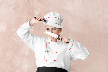 Mature female chef with knives on color background