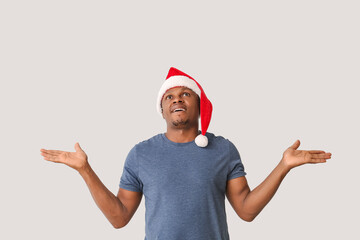 African-American man in Santa hat on light background