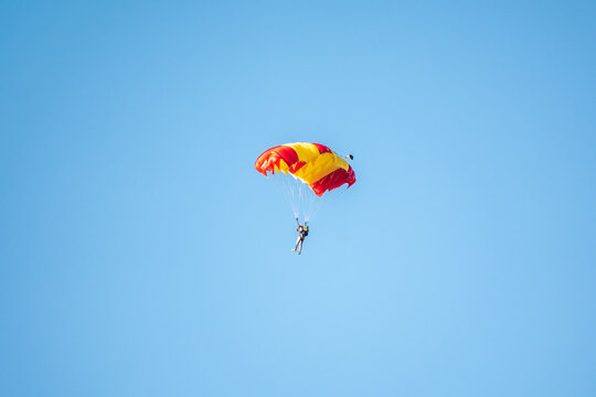 One parachutist floats slowly at low altitude on the background of clear sky
