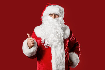Santa Claus showing thumb-up on color background. Christmas vacation