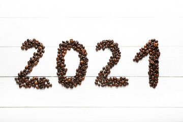 Figure 2021 made of coffee beans on white wooden background