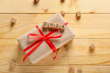 Gift box and sugar cubes with figure 2021 on wooden background