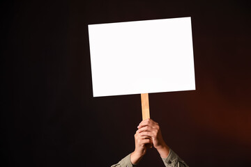 Protesting woman with placard on dark background