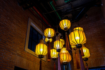 Contemporary illuminating electric lamps in a hall against brown brick wall.
