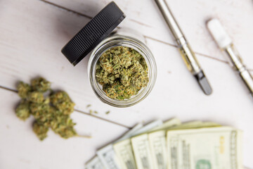 medical cannabis herb and vape pens on money on table