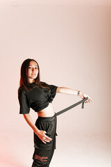 girl of Asian appearance on a pink background, holding a waist belt in her hands