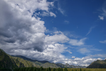 Mountain range against blue sky with white clouds. Beautiful landscape on summer day. Majestic rocks in the sunlight. Natural backgrounds.