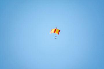 Fototapeta na wymiar One parachutist floats slowly at low altitude on the background of clear sky