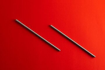 Reusable steel drinking straw in metallic color on red background