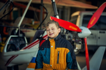 Portrait of a boy in a hangar with planes. Childhood dreams of aviation