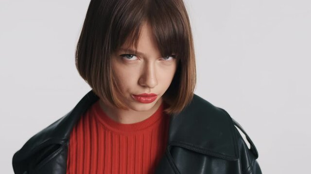 Gorgeous fashion girl with bob hair and red lips posing on camera with devil look over white background. Dangerous girl