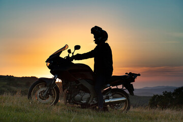 Naklejka na ściany i meble Man on his motorbike riding into sunset