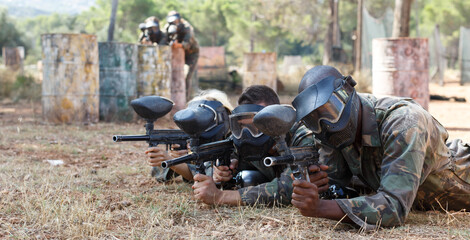 Fototapeta premium Portrait of team of adult people playing on paintball battlefield area outdoor