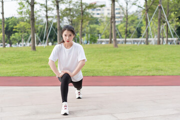 Obraz premium Young long-haired woman is doing exercises in the park 
