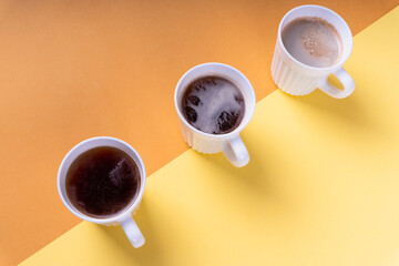 Three cups of different coffee on color background.