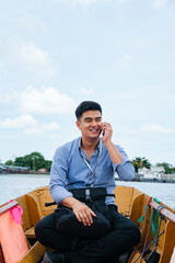 Asian business man talking on the phone travel by a boat in Bangkok.