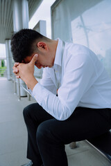 Stressed businessman feel sick and tired while waiting for transportation at bus stop.