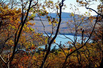 Scenic blue lake surrounded by hills covered with trees in fall colours