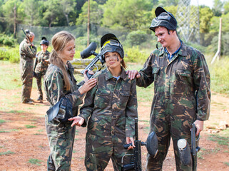 Paintball team calming upset girl after the losing match on open playing field