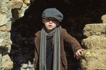 Retro portrait of a boy in a cap ,corduroy jacket and scarf on the street - 385671531