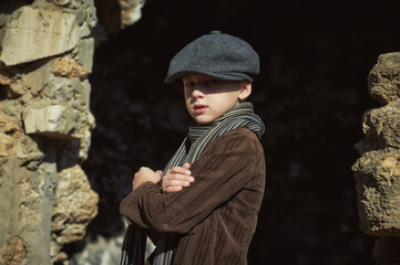 Retro portrait of a boy in a cap ,corduroy jacket and scarf on the street - 385671533