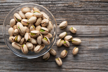 Pistachios in a bowl set against an old wooden backdrop