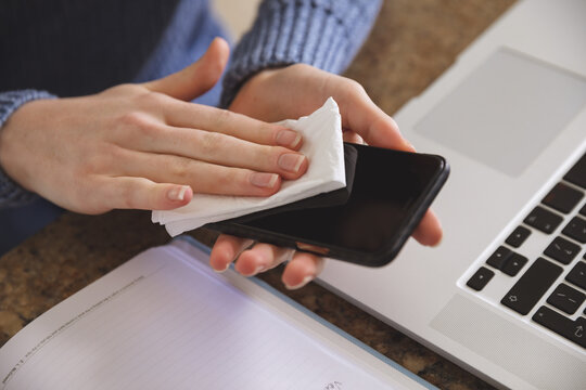 Mid section of woman wiping her smartphone with a tissue