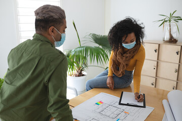 Woman wearing face mask taking notes in office