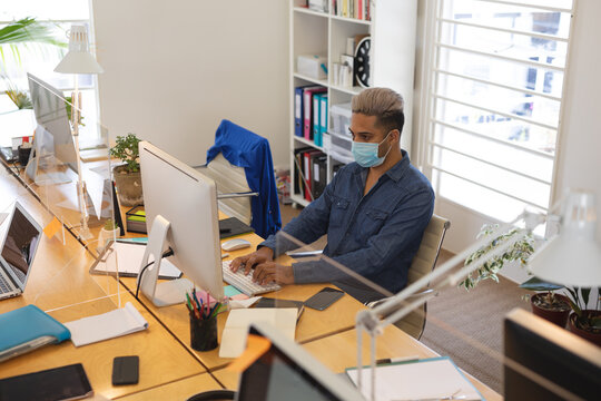Man wearing face mask using computer at office