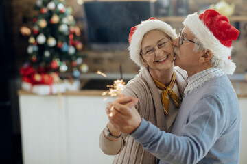Loving senior couple dancing on Christmas day at home.