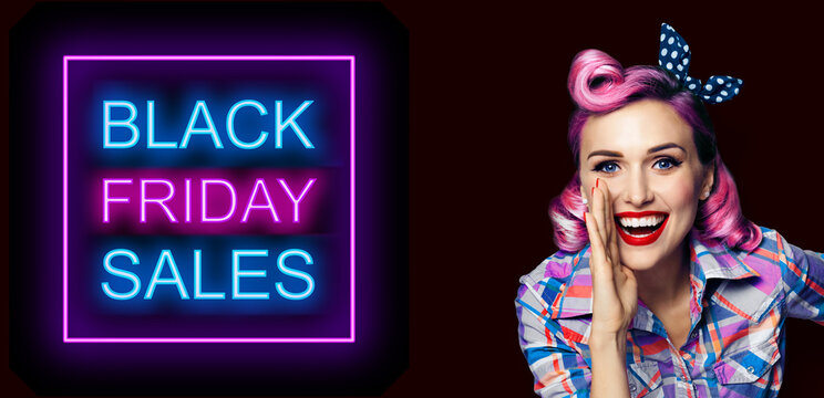 Beautiful happy excited woman holding hand near open mouth. Girl dressed in pin up. Blond model at retro fashion vintage concept, over dark background. Black Friday sales neon light sign.