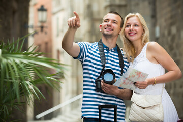 Obraz premium Traveling man and girl walking together with luggage and looking around in city
