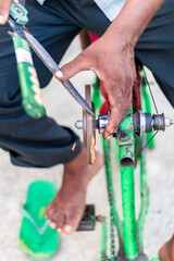 Fototapeta na wymiar Closeup hands of a man sharpening a knife on a DIY makeshift sharpening machine on a bicycle frame.