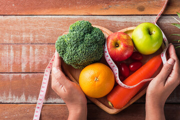 fresh fruit and vegetable in heart plate and woman use hands hold the plate