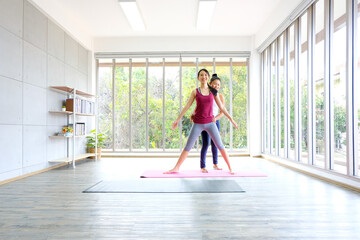 Asian female yoga trainer  helping her trainees  stretching making tilts to the side before practice ,yoga at home,full length, Concept of healing body and spirit.Exercise at home