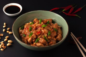 Kung Bao chicken on a black background. A Chinese dish with chicken, chili, peanuts, sauces and onions.