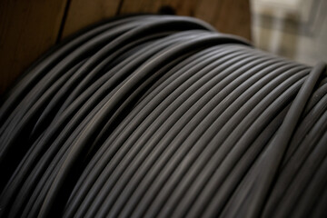 Vertical coils ndustrial wires. Many turns of main electrical cable is closeup. Roll of outdoor...