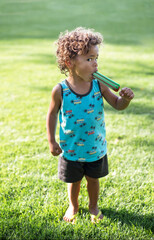 Cute African American Boy eating a giant popsicle outdoors in the summertime. He takes a big bite of a cool snack on a warm summer day