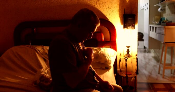 Man lying down in bed and turning night lamp off, old man going to sleep