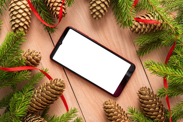 On the Christmas table is a phone and fir cones with branches.