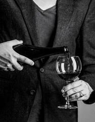 Sommelier man, degustator, winery, male winemaker. Bottle, red wine glass. Pouring red wine from...