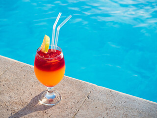 Obraz premium Beautiful glass with a cocktail on the background of the pool. View from above, close-up. Concept of leisure and travel