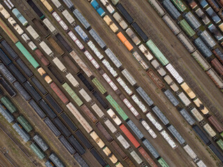 Cargo trains close-up. Aerial view of colorful freight trains on the railway station. Wagons with goods on railroad. Heavy industry. Industrial conceptual scene with trains. Top view from flying drone