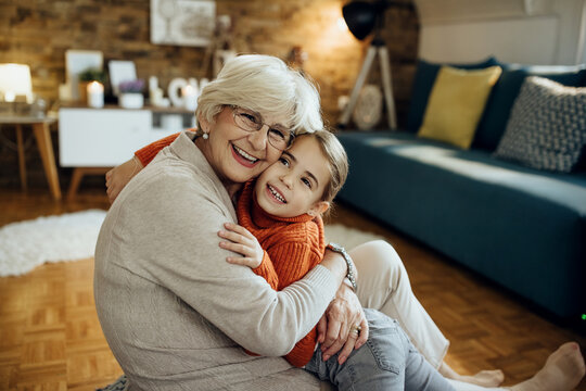 Loving grandmother and granddaughter embracing at home.