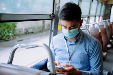 Fototapeta na wymiar Business man wear mask using smartphone on a bus.
