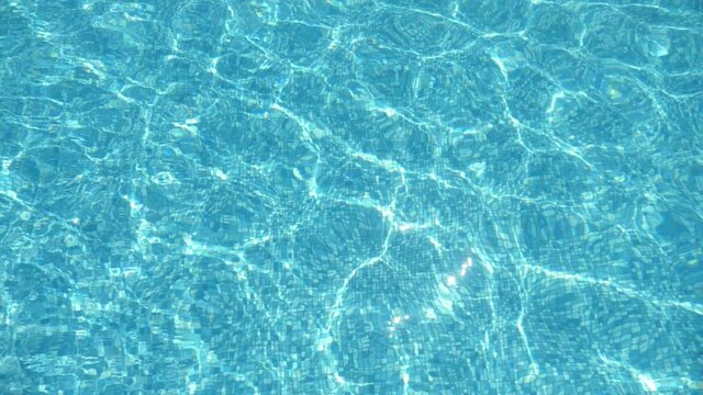 Transparent waves are moving almly in swimming pool on sunny day in summer   