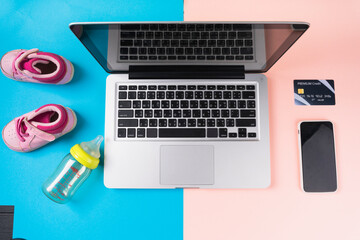 Computer laptop with empty screen on blue and pink background with kid accessories.