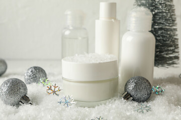 Fototapeta na wymiar Concept of face care with cosmetics on background with decorative snow
